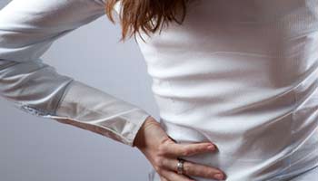 A woman holding her back in pain from kidney issues. 
