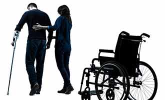 A man with a walking cane being helped out of his wheelchair.  