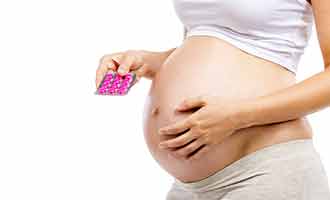 A woman holding a packet of pink pills. 