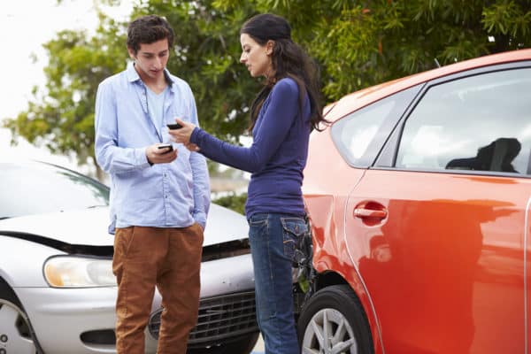 Man and woman exchanging insurance information at scene of a car accident
