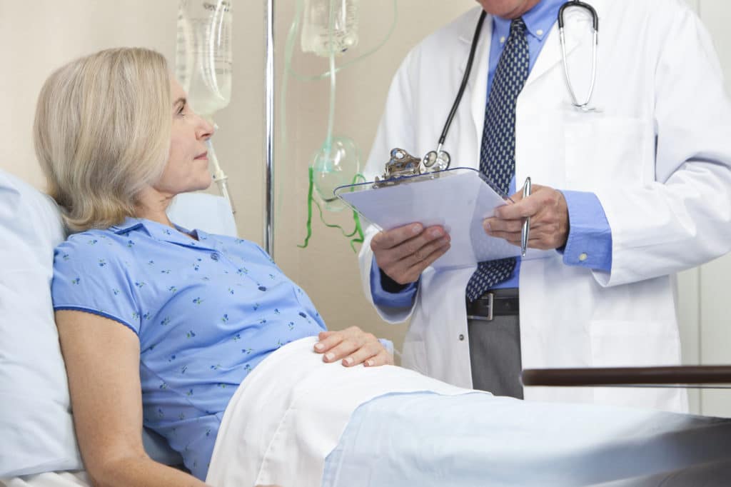 A doctor visiting a woman in a hospital bed.