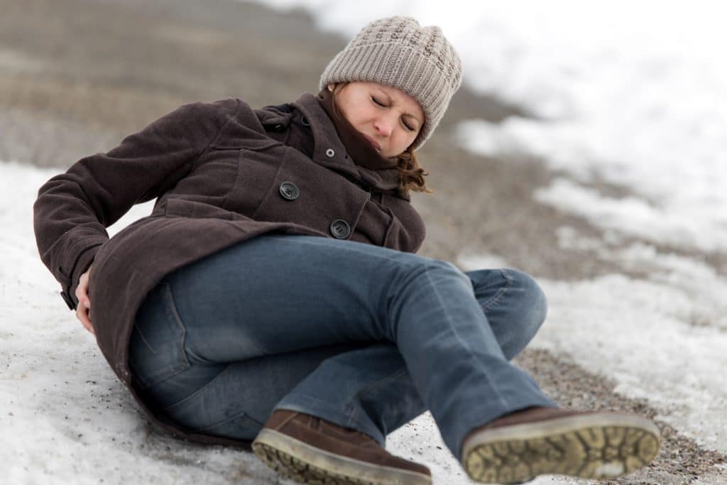 A woman slipping and falling on icy pavement.