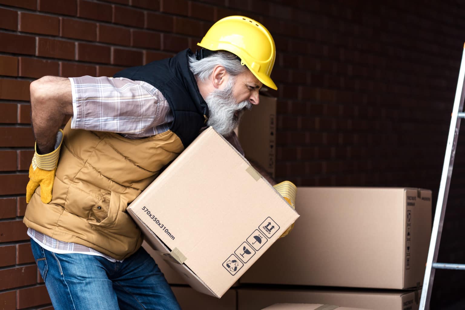 Worker hurting back while picking up a box