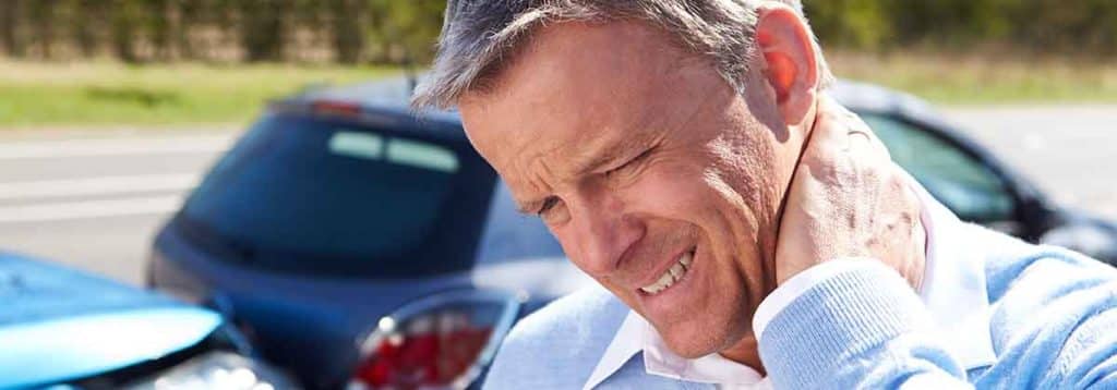 A man holding his neck in pain after a car accident.