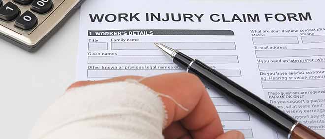 A bandaged hand next to a Work injury claim form.
