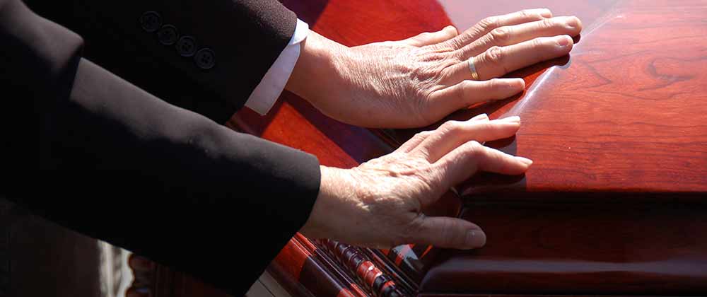 hands on casket of wrongful death victim