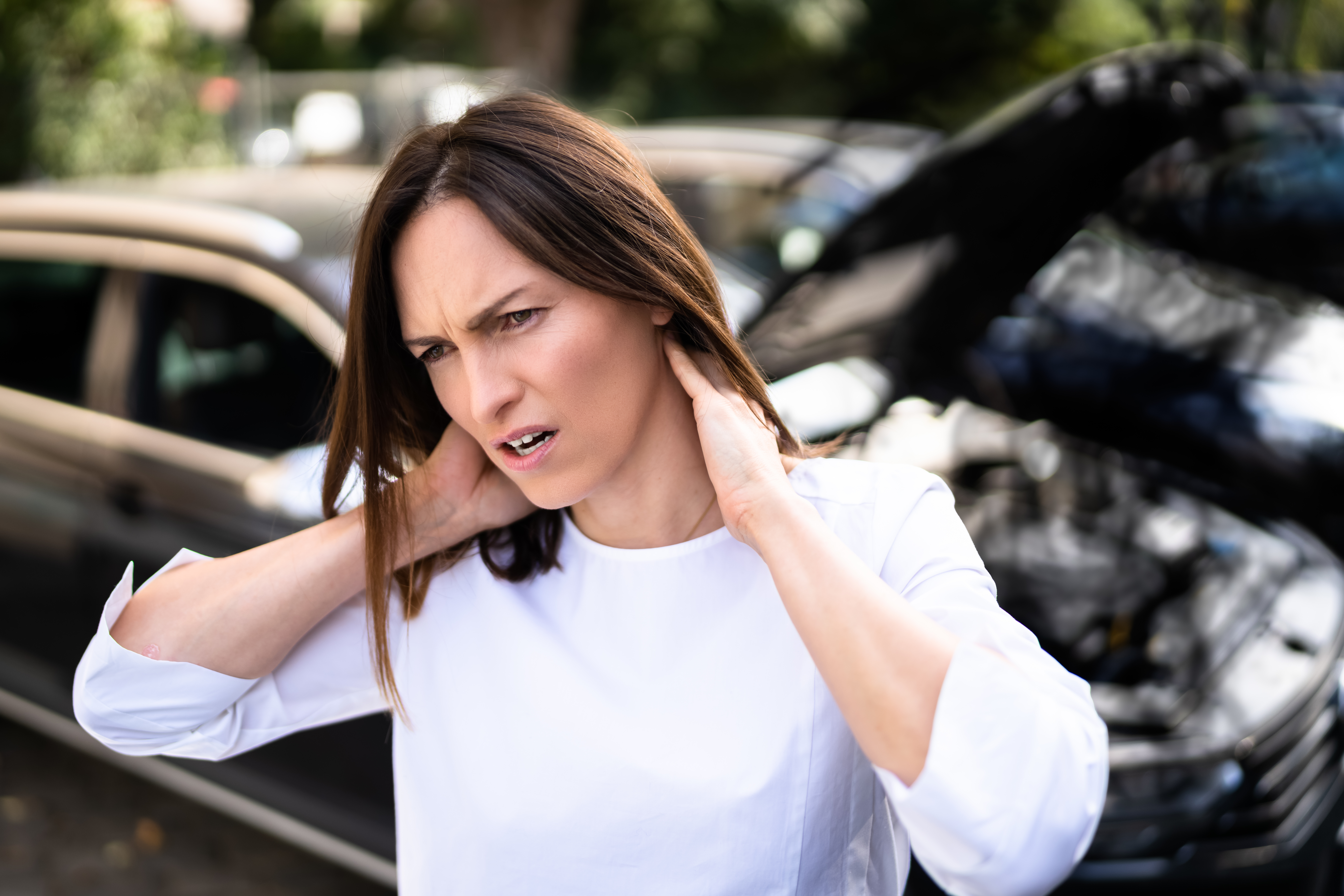 A woman suffering a neck injury at a car accident scene.