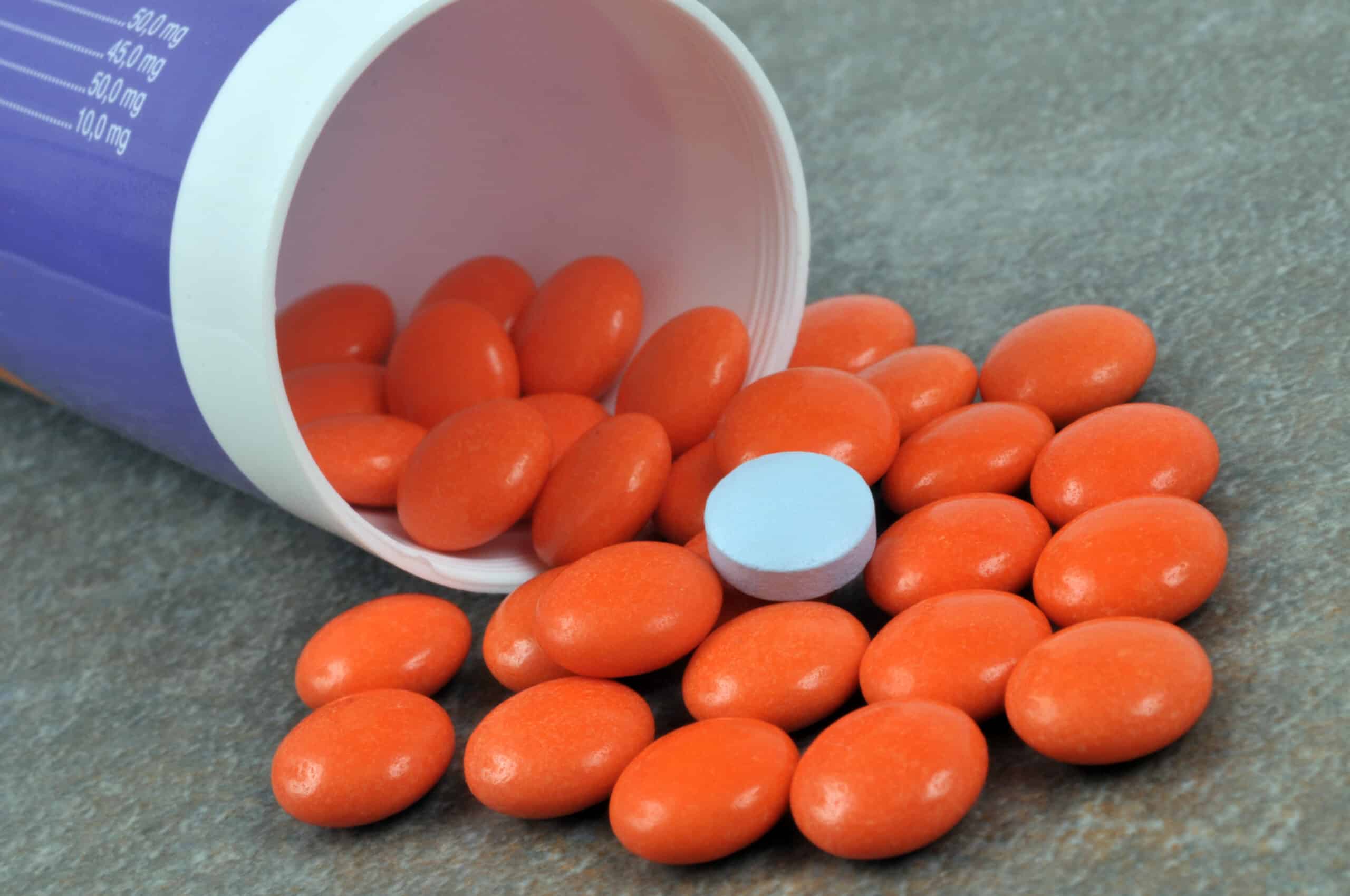A bottle of pills, spilled on the ground.
