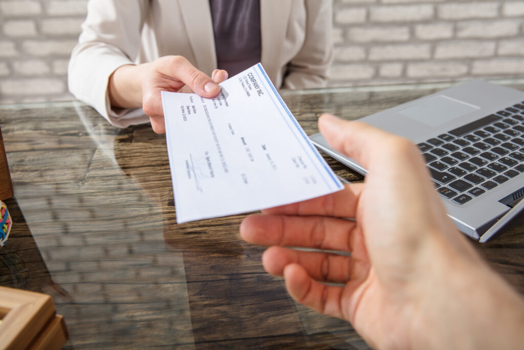 A lawyer handing a settlement check to a client.