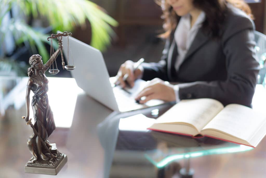 A lawyer at her desk with a laptop and book.
