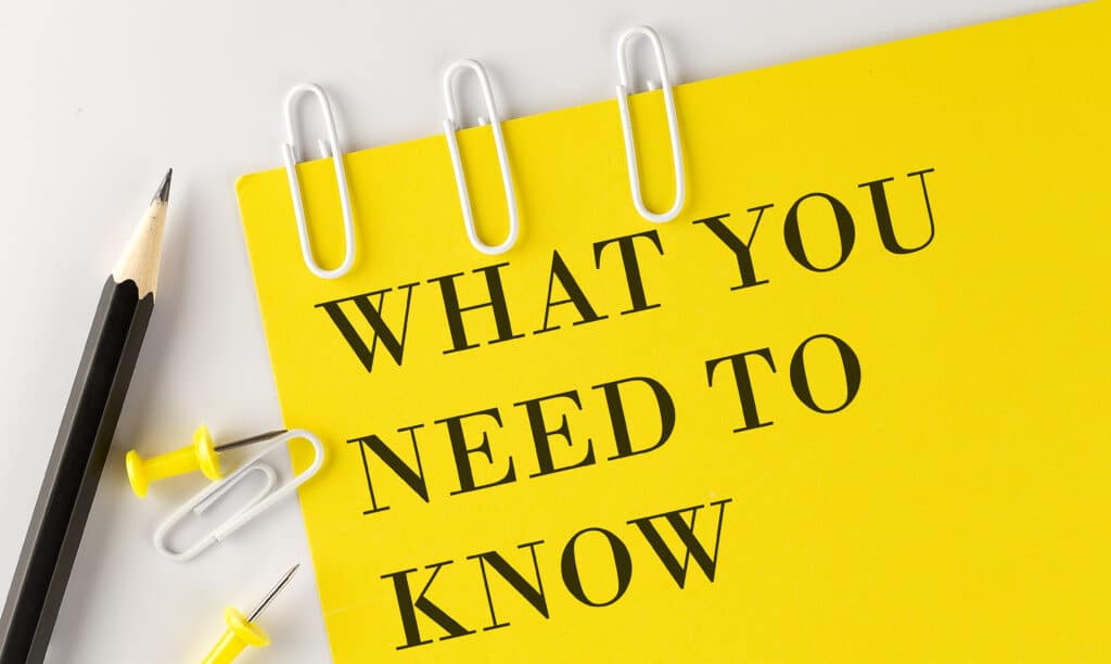 WHAT YOU NEED TO NOW word on yellow paper with office tools on a white background